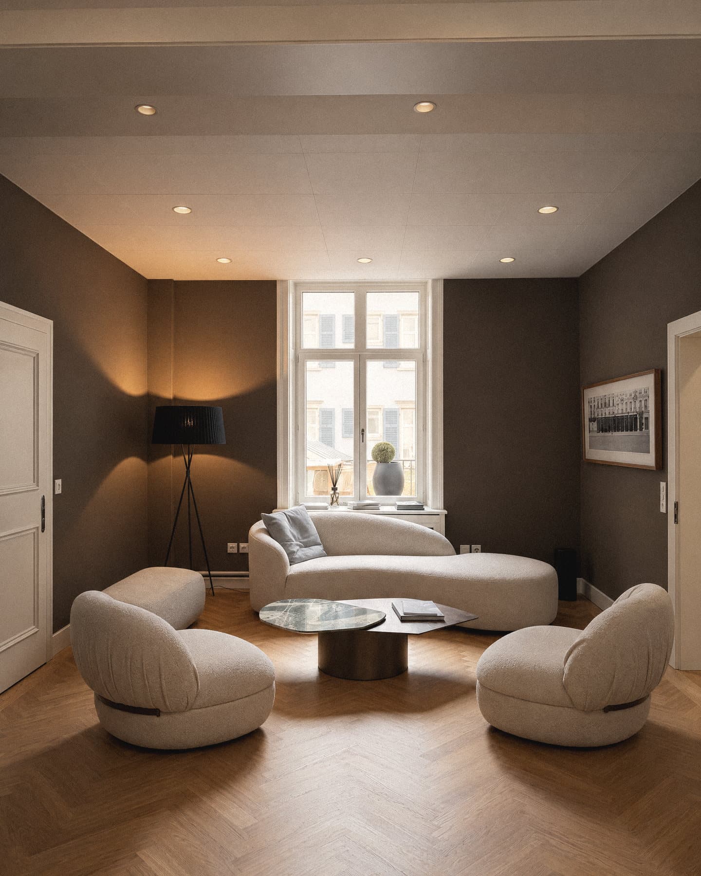 The lounge at Talstrasse 37: herringbone parquet, a curved sofa and two armchairs at the bay window